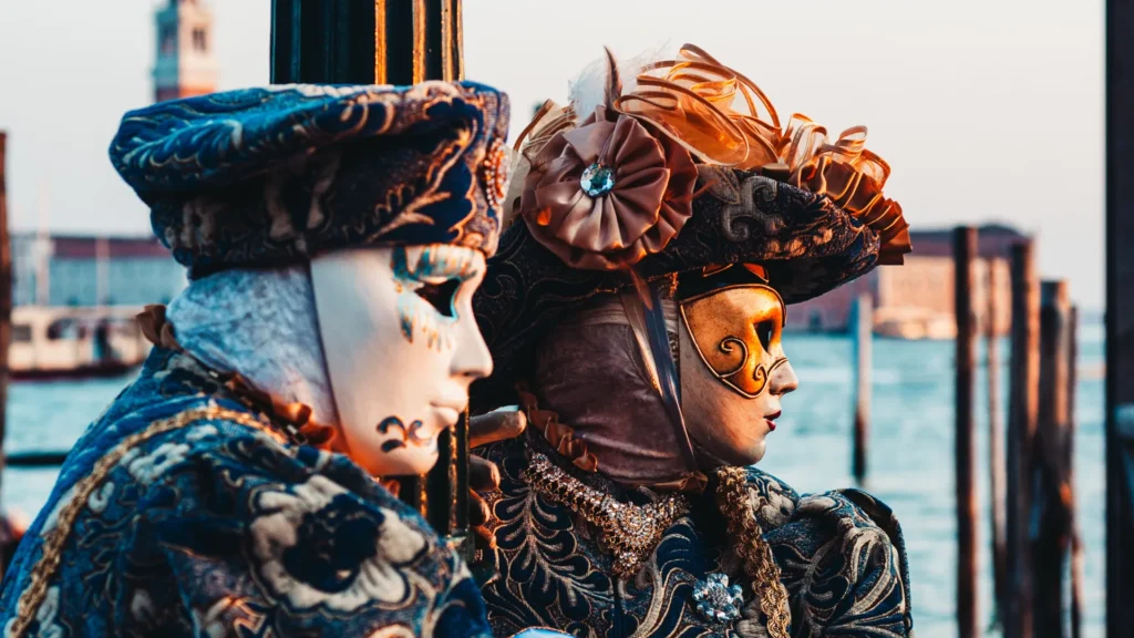 Nell'immagine due persone vestite con i tipici costumi del carnevale di Venezia con un canale sullo sfondo